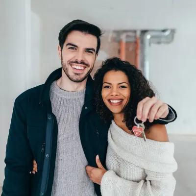 Lachend koppel met de sleutel van hun nieuwe woning Lachend koppel met de sleutel van hun nieuwe woning