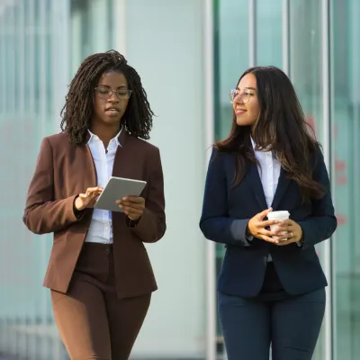 Twee vrouwelijke collegas die iets met elkaar bespreken Twee vrouwelijke collegas die iets met elkaar bespreken