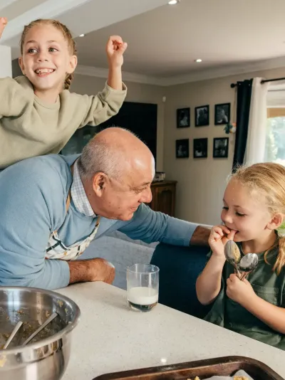 Opa die met zijn twee kleindochters in de keuken staat